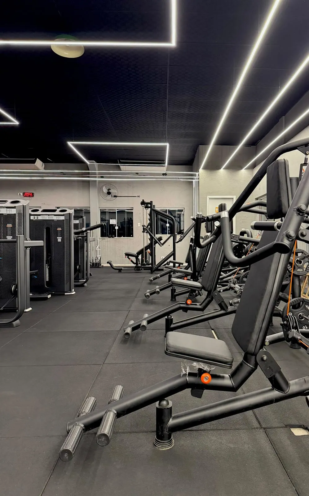 Sala de musculação da FitCompany São Pedro com máquinas articuladas e iluminação em LED no teto